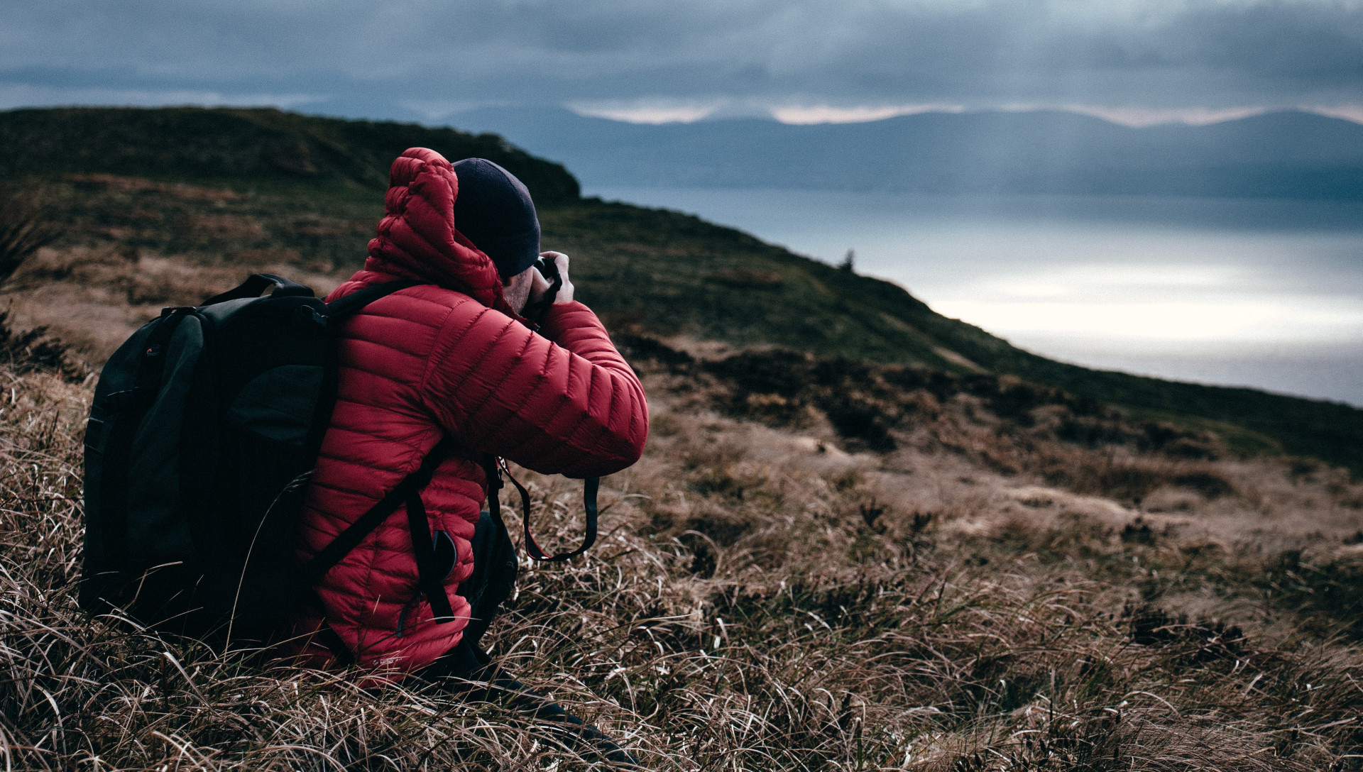 Foto einer Person in roter Jacke, welche die Landschaft fotografiert.
