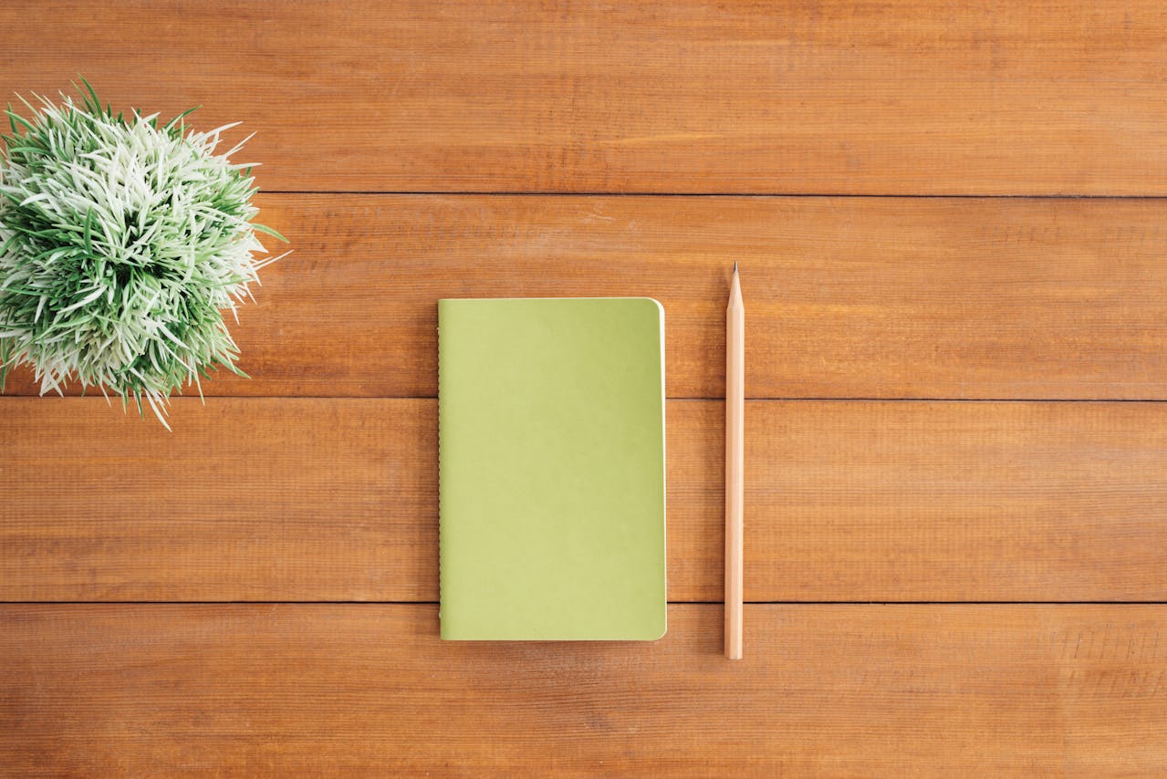 A notebook and a pencil on a wooden table.